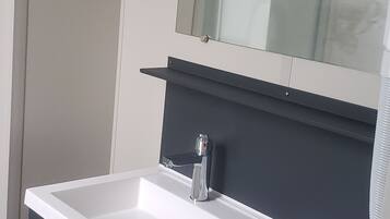 A modern bathroom with a white sink, dark countertop, and a mirror above.