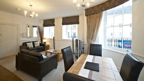 A modern living room with a sofa set, a dining table, and a TV. - Villetts House (Swindon)