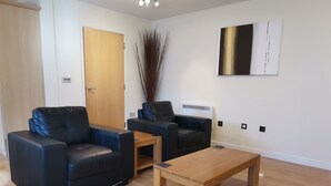 A modern living room with two black leather sofas, a wooden coffee table, and a minimalist decor. - Villetts House (Swindon)