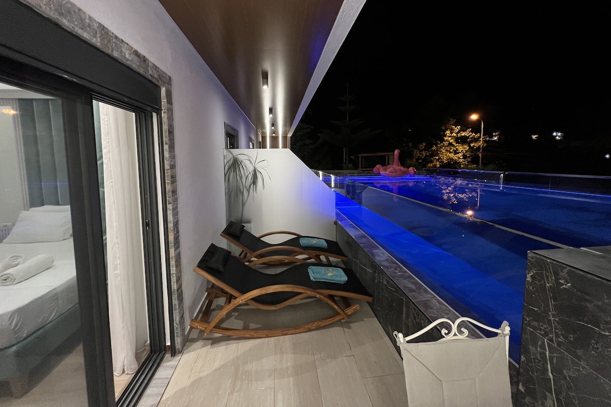 A modern hotel room with a balcony overlooking a swimming pool.