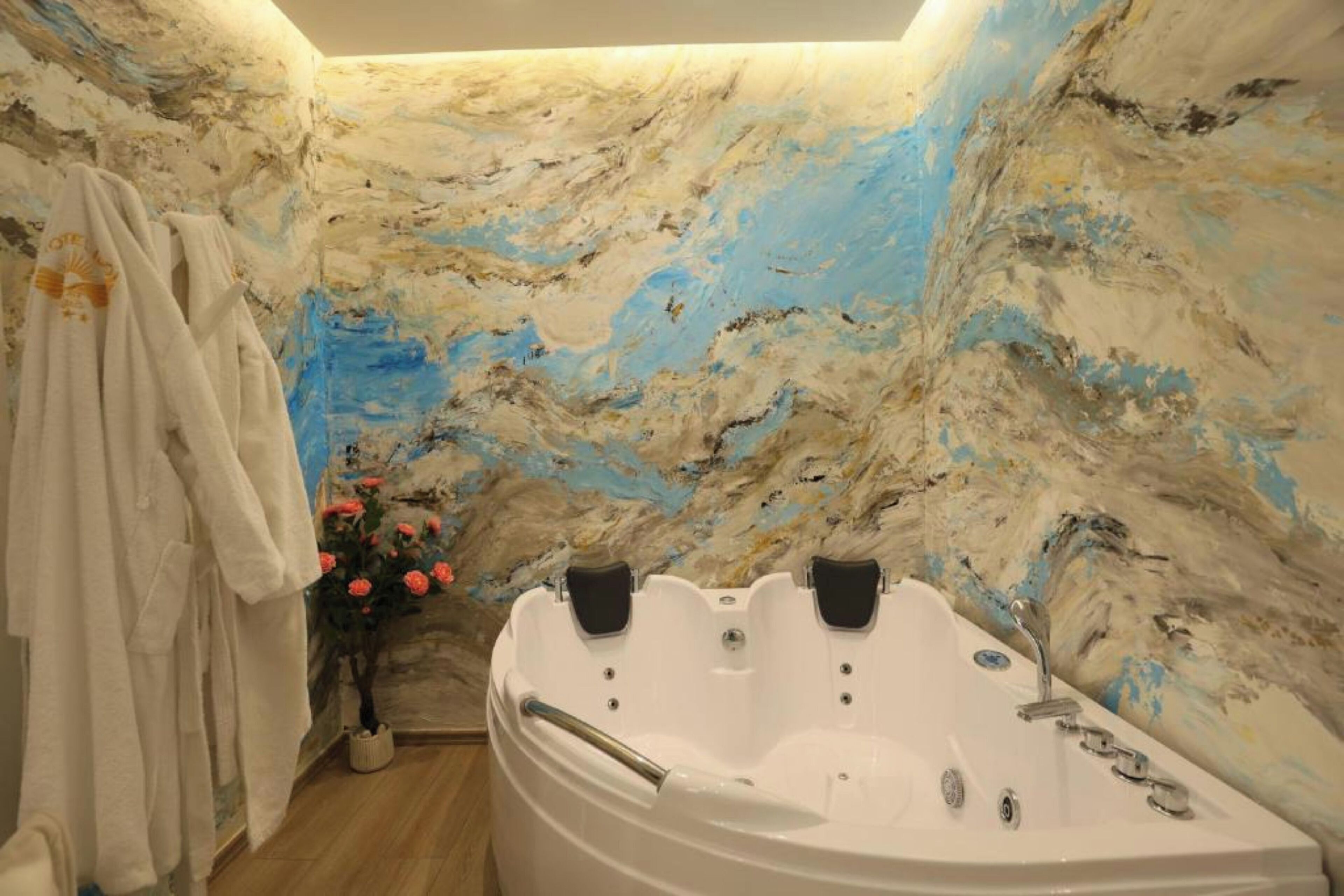 Ein Badezimmer mit Marmorwand, einer Badewanne und einer Blumenvase.