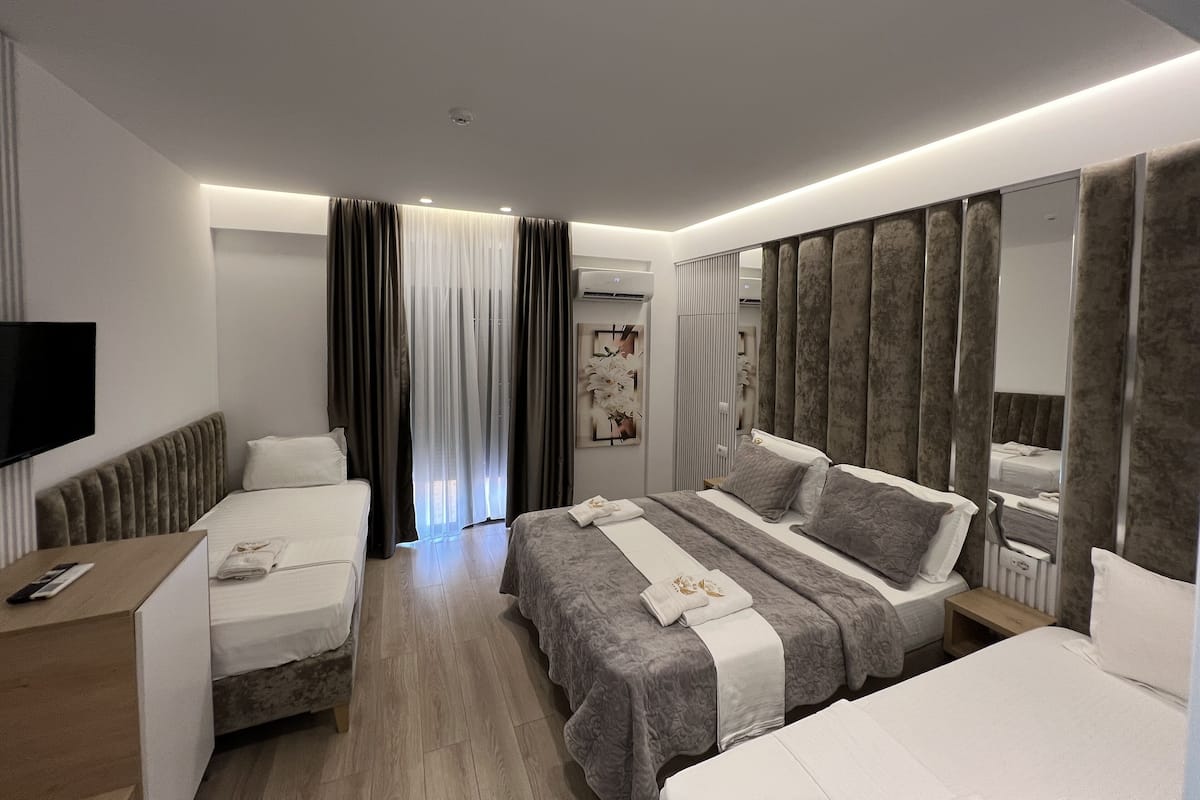 A modern hotel room with two beds, a desk, and a TV.