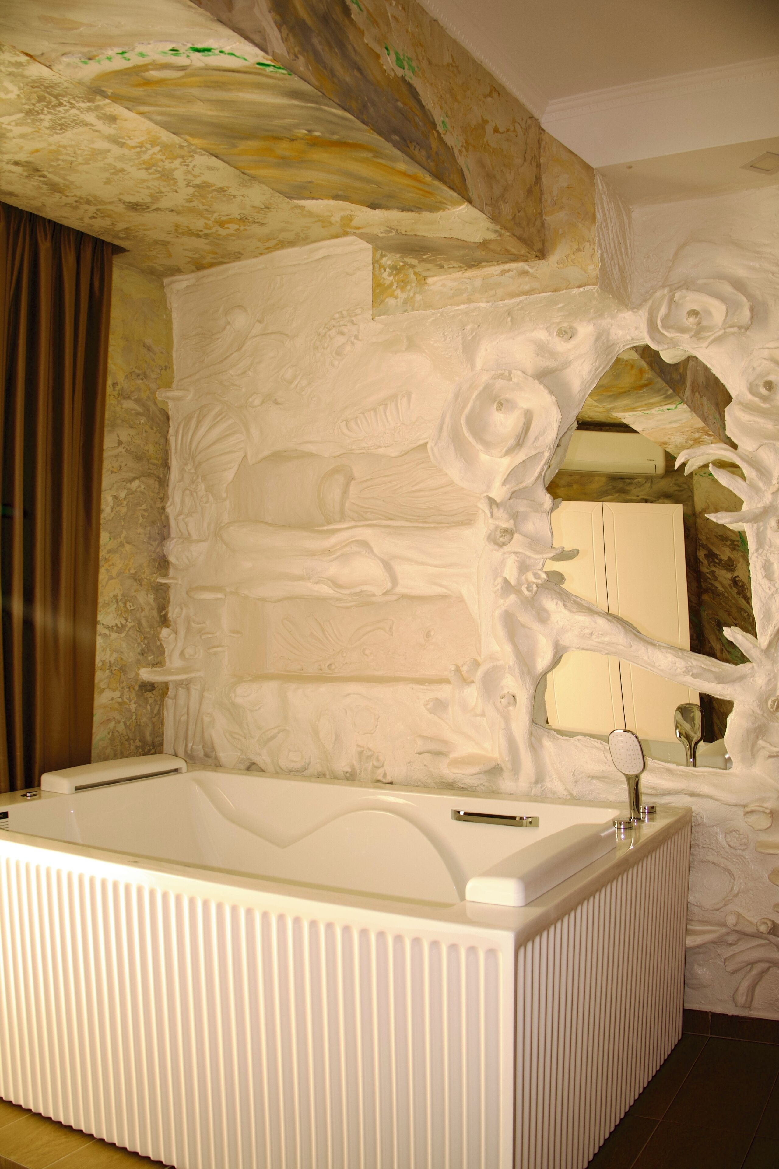 Une salle de bain avec une grande baignoire, un miroir et un mur à motifs.