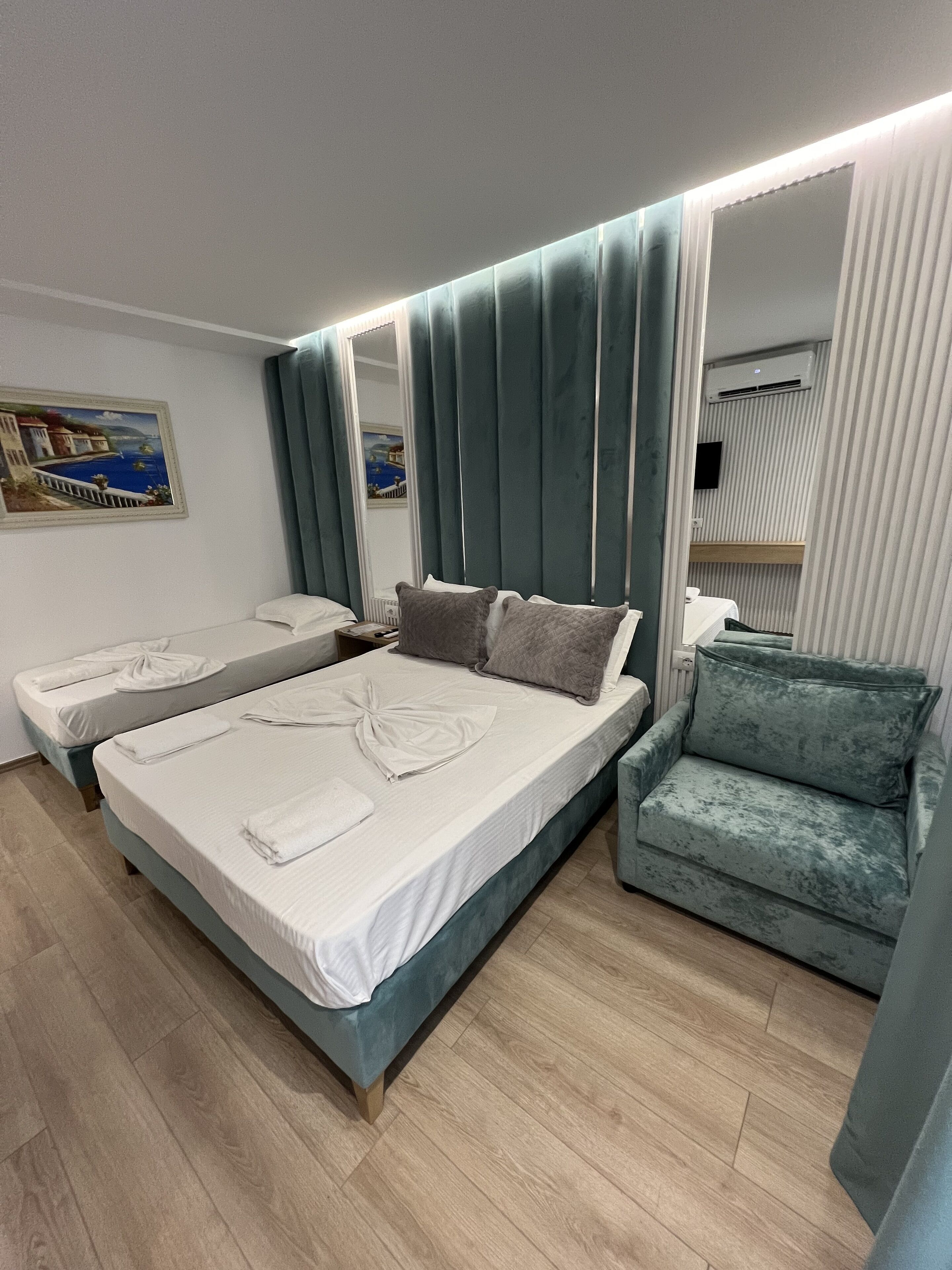A modern hotel room with a large bed, a seating area, and a mirror.