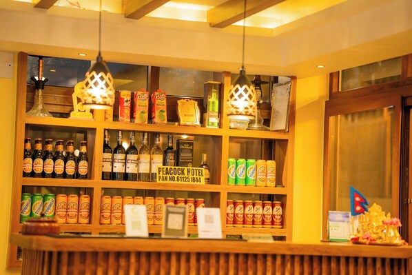 A bar area with shelves of bottled beverages, a sign for Peacock Hotel, and a decorative item on the counter.