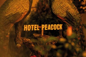 A decorative peacock statue with the text 'HOTEL PEACOCK' prominently displayed. - Hotel Peacock (Sauraha)