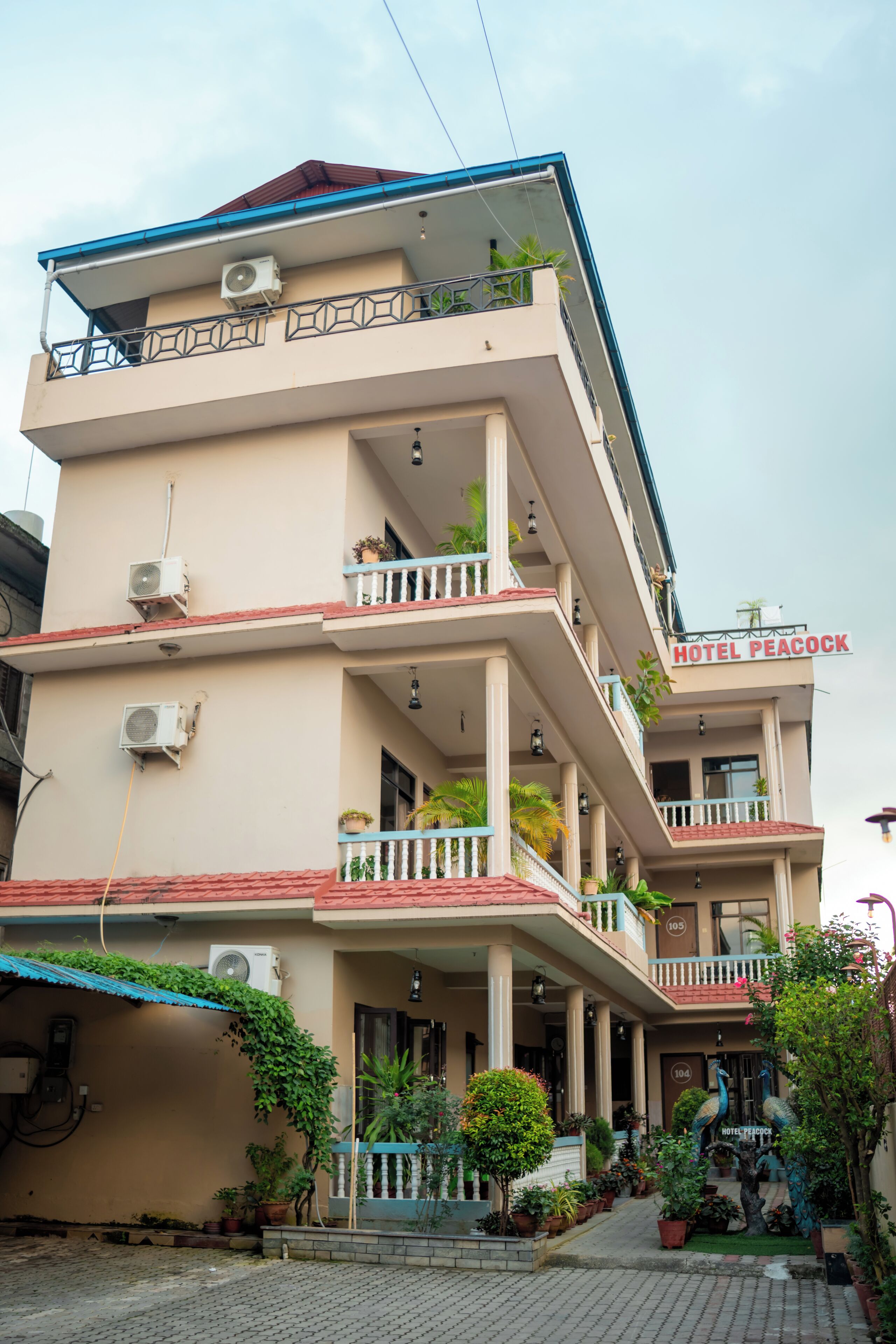 A multi-story hotel with balconies, air conditioning units, and a sign reading 'Hotel Peacock.'