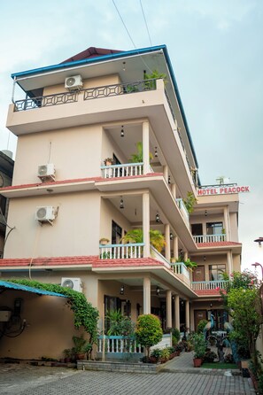 A multi-story hotel with balconies, air conditioning units, and a sign reading 'Hotel Peacock.' - Hotel Peacock (Sauraha)