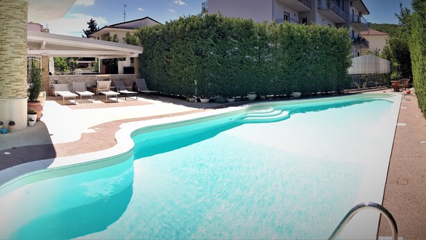 Une piscine avec des chaises longues et un espace patio couvert.
