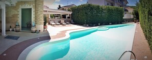 Ein Schwimmbecken mit Liegestühlen und einer überdachten Terrasse.
