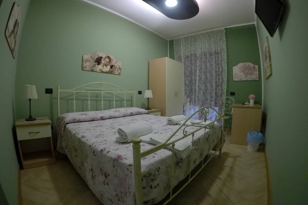 Ein Schlafzimmer mit Bett, Nachttisch, Schrank und einem Fenster mit Vorhängen.