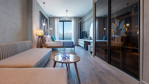Ein modernes Hotelzimmer mit einer Couch, einem kleinen Tisch, Bergblick und einem großen Fenster.