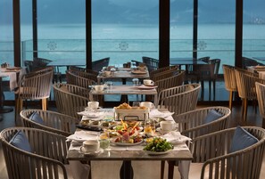 A dining area with a table set for a meal, overlooking a body of water.