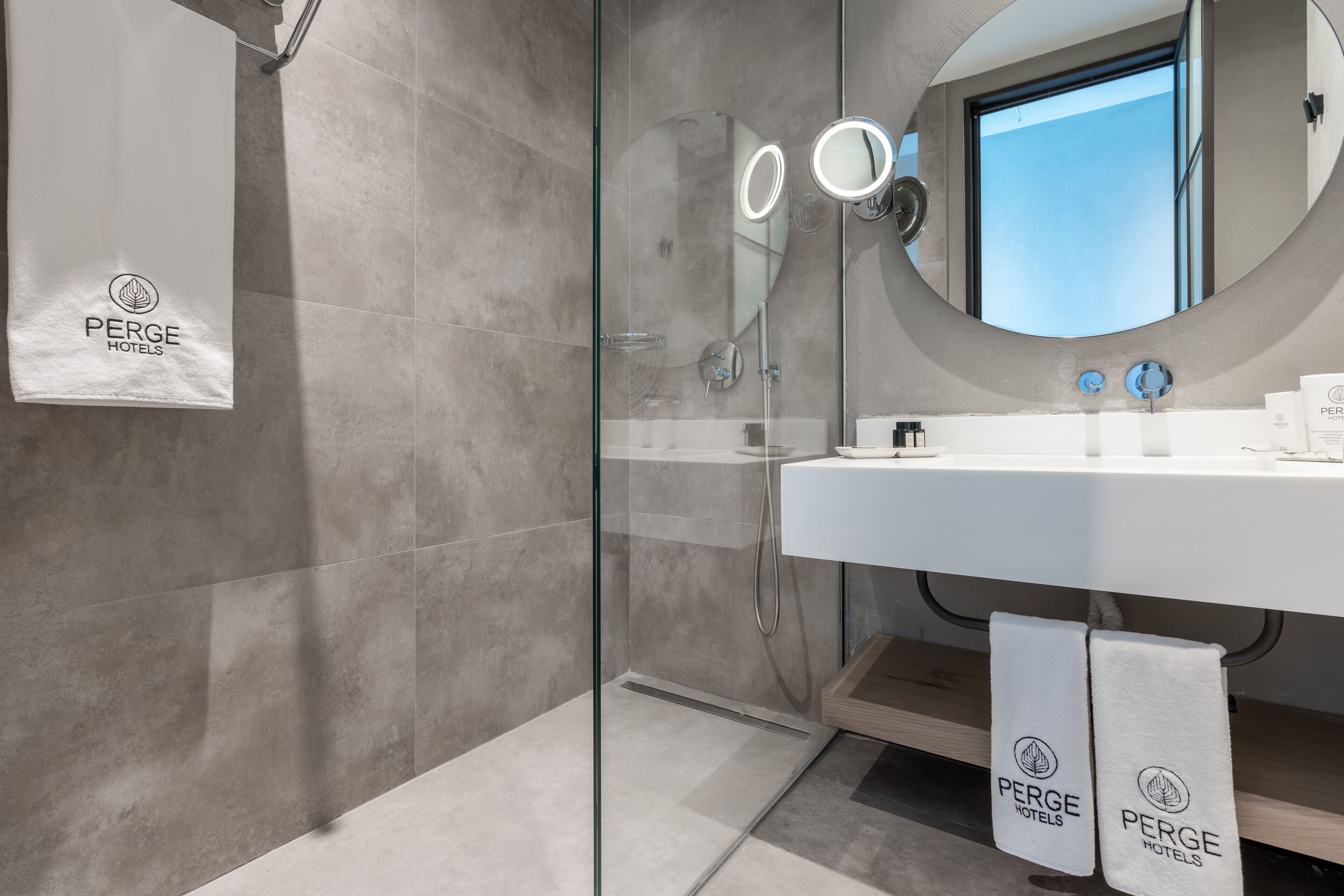 A modern bathroom with a glass-enclosed shower, a large mirror, and a sink with a towel rack.