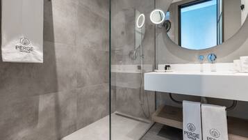 A modern bathroom with a glass-enclosed shower, a large mirror, and a sink with a towel rack.