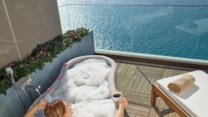 Eine Person entspannt sich in einer Badewanne mit Blick auf das Meer.