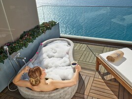 A person relaxing in a hot tub with a view of the sea.