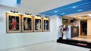 A reception area with a tiled floor, a reception desk, and three framed artworks on the wall.