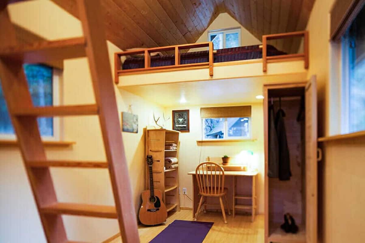 Ein gemütliches Zimmer mit Schlafkoje, Schreibtisch, Stuhl und Gitarre.