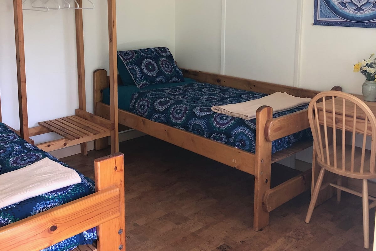 Eine kleine, einfache Unterkunft mit Etagenbett, Einzelbett und Holzstuhl.