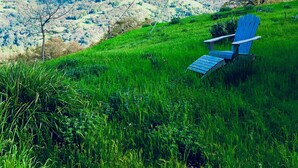 Une chaise sur une colline herbeuse, d’où l’on a une vue sur une vallée et des montagnes.
