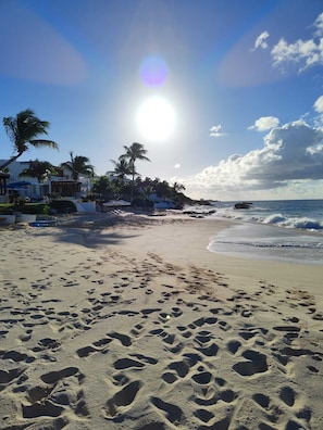 Ein Strand mit Fußspuren, Palmen und blauem Himmel.