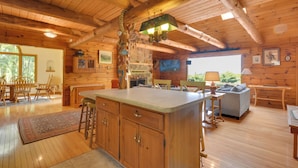 A wooden cabin interior with a kitchen, dining area, and living room.