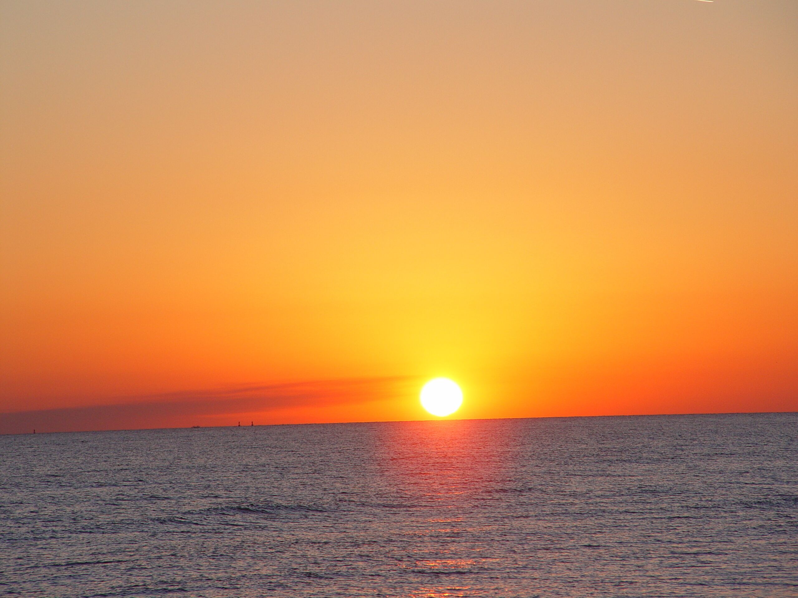 A sunset over a calm sea with a clear horizon.