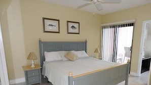 Ein Schlafzimmer mit einem Bett, zwei Nachttischen, einem Deckenventilator und zwei gerahmten Bildern an der Wand.