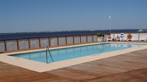 Eine Holzterrasse mit Pool und Meerblick.