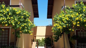 A courtyard with two buildings, a wooden bench, and a small staircase. - Charming house in a gated community in Juquehy. - 2 suites (São Sebastião)