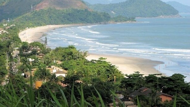 A coastal landscape with a beach, greenery, and hills in the background. - Charming house in a gated community in Juquehy. - 2 suites (São Sebastião)