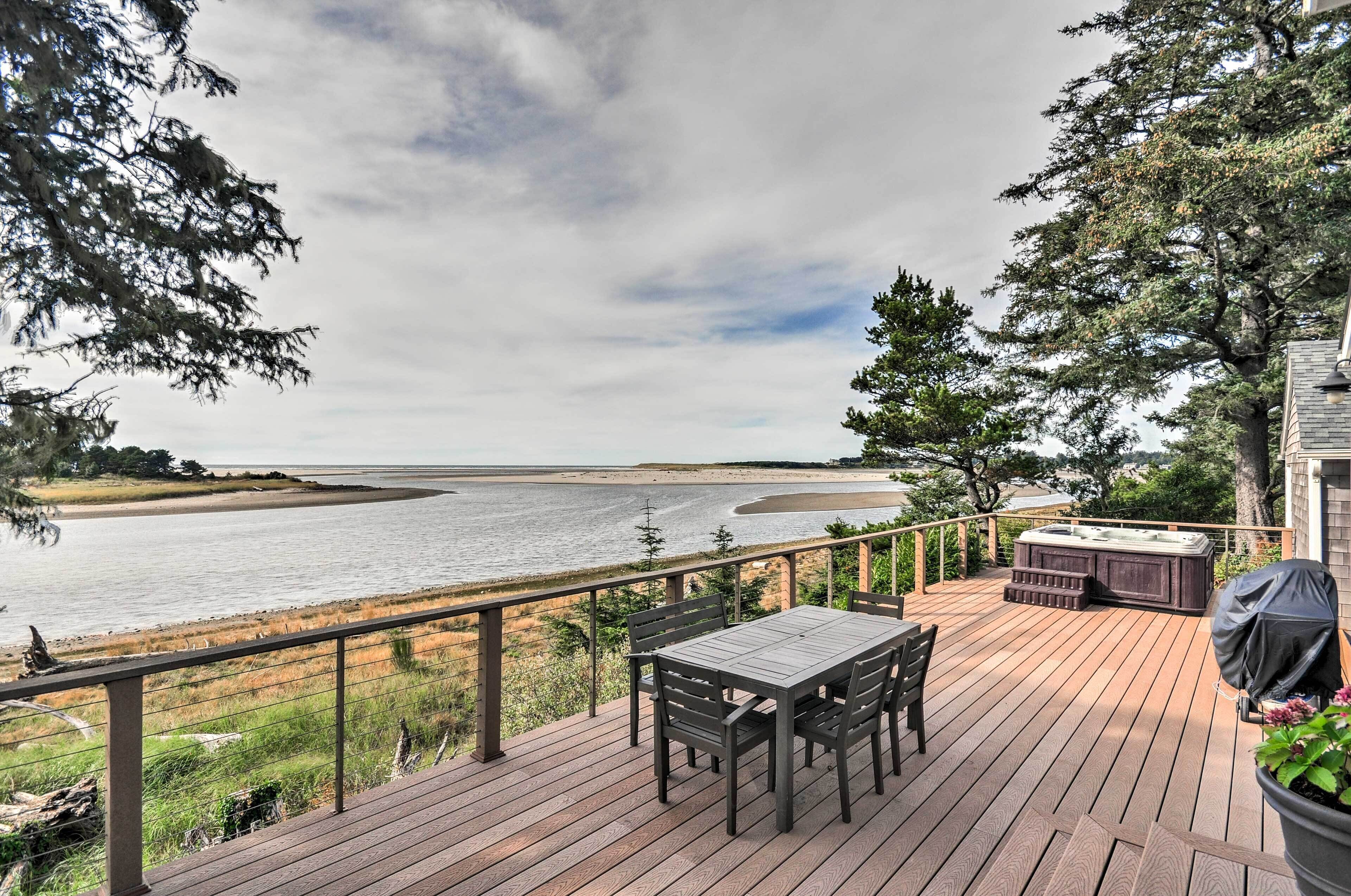 Terraza de madera con mesa y sillas, con vista a un río.