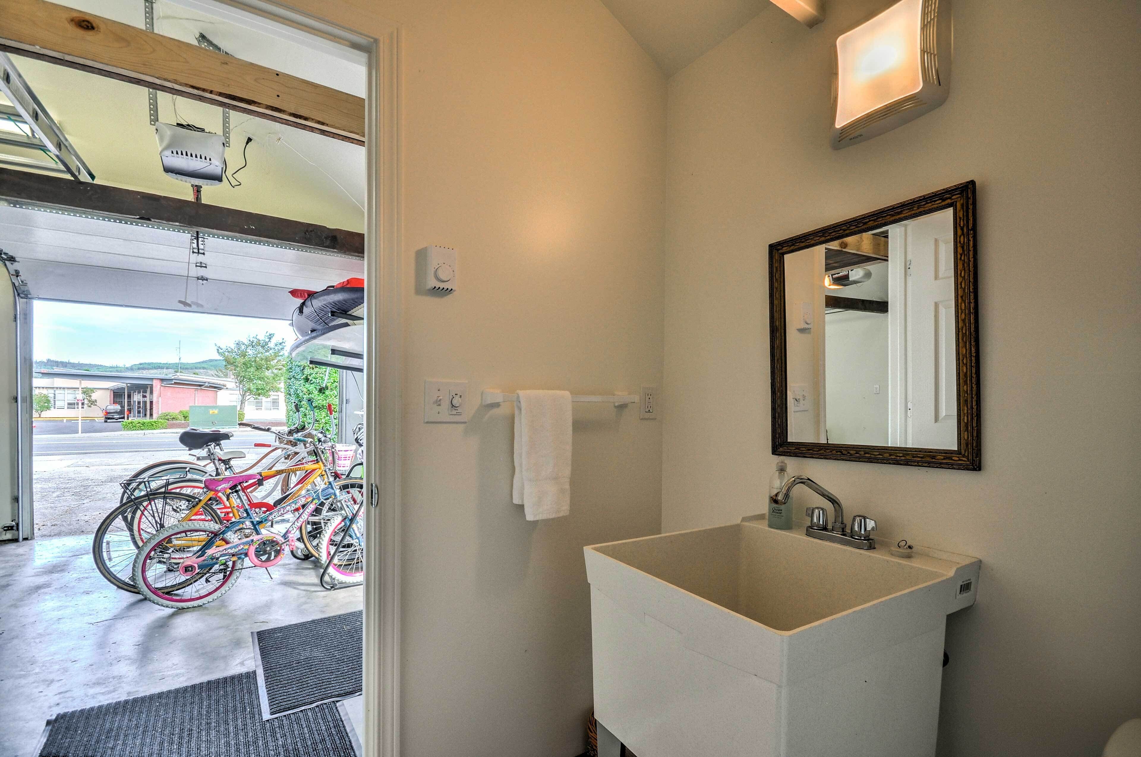A bathroom with a sink, mirror, and a towel rack. There are bicycles parked outside the bathroom.