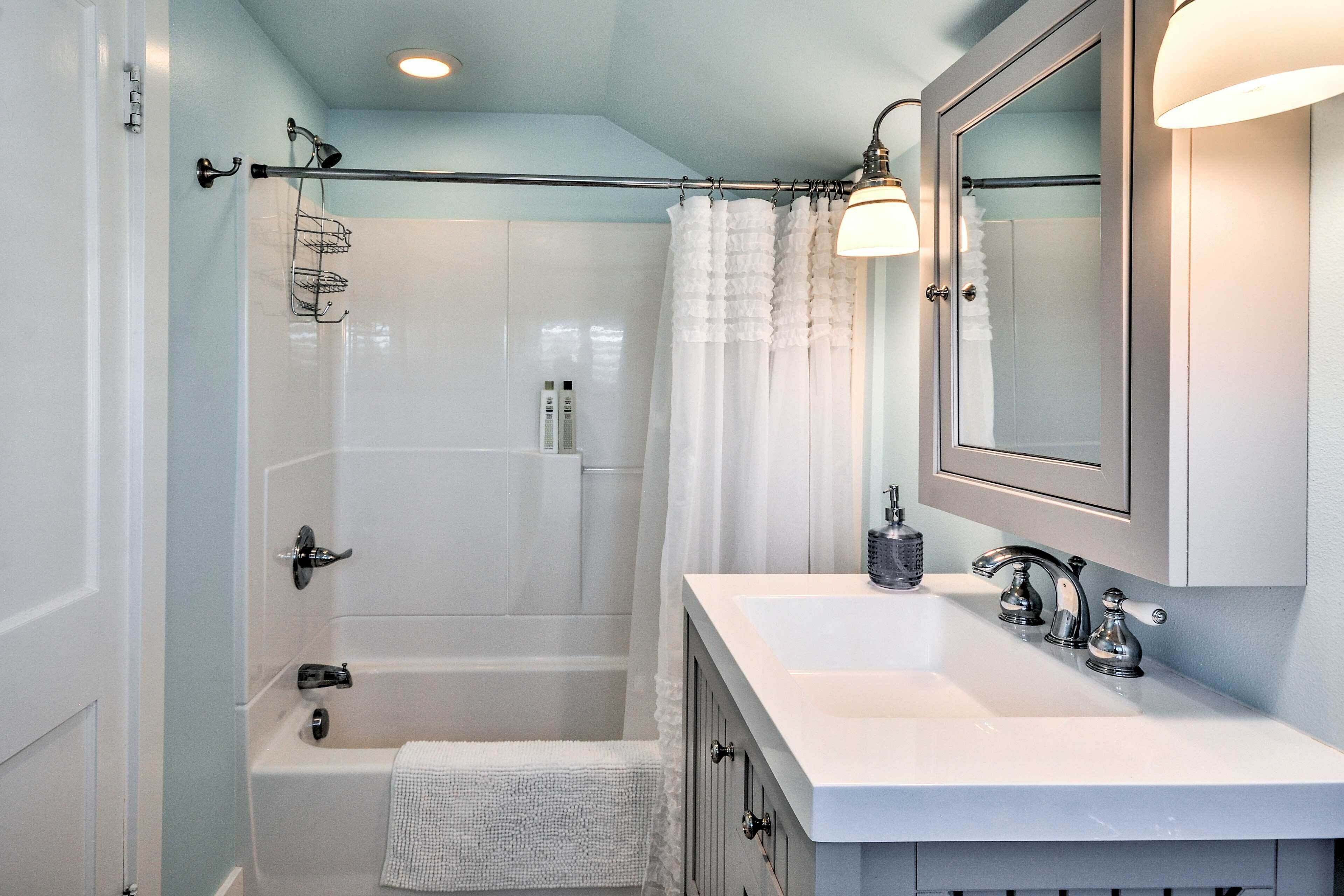 A modern bathroom with a bathtub, a double sink vanity, and a large mirror.