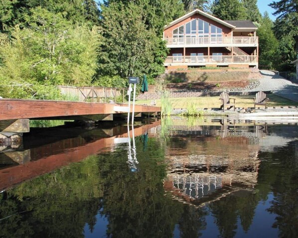 A lodge with a large deck and a pond in front.