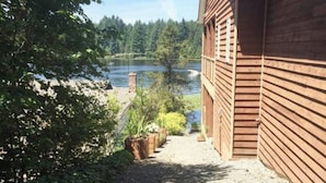 A wooden building with a gravel path leading to a lake. - Lakeside Living Suite! ~Mt. Rainier, NWTrek, JBLM (Graham)