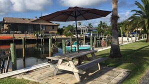 A waterfront property with a dock, a wooden picnic table, and a large umbrella.