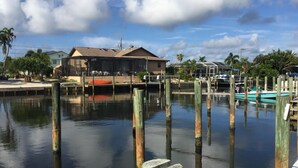 A marina with docked boats, a house with a covered patio, and a clear sky.