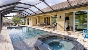 A covered swimming pool with lounge chairs and a hot tub, surrounded by a patio area. - House Aruba by Vacationhit (Cape Coral)