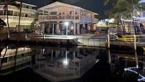 Une propriété située au bord de l’eau, avec une grande maison, une piscine et des palmiers.