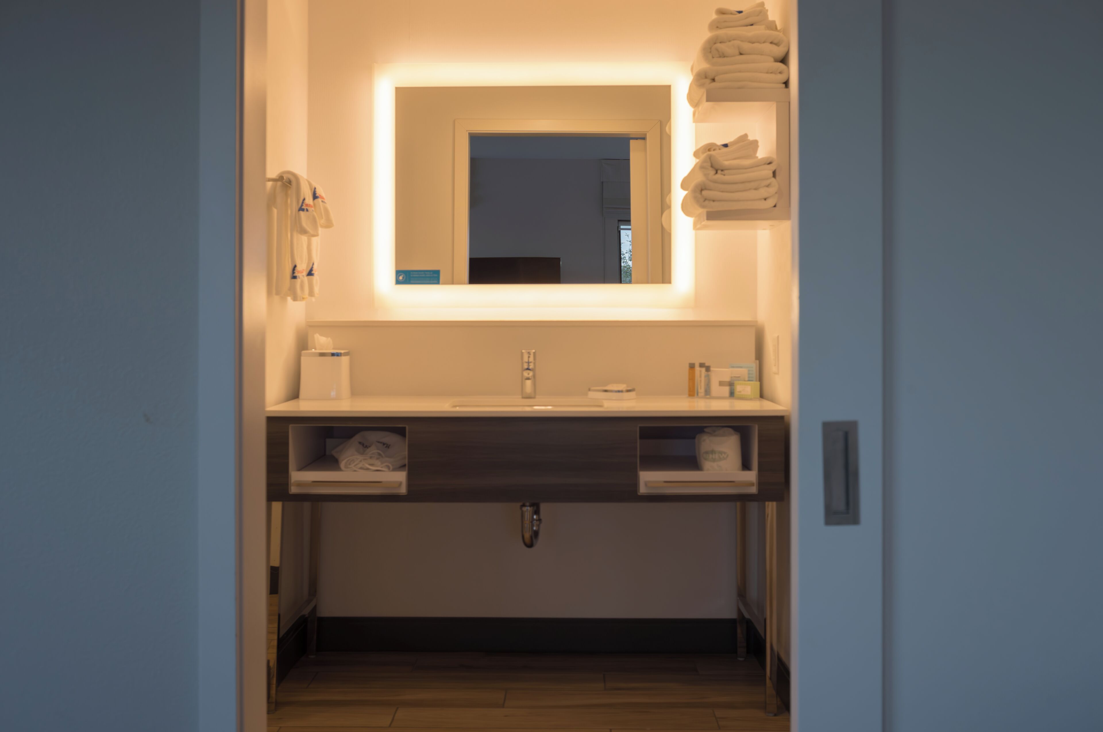 Ein modernes Badezimmer mit großem Spiegel, Waschbecken und Handtuchhalter.