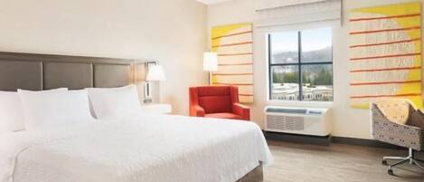 Habitación de hotel con una cama grande, una silla roja, un escritorio y una ventana con vistas.