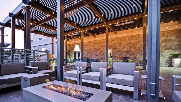 Un patio al aire libre con mobiliario moderno, una chimenea y luces colgantes.