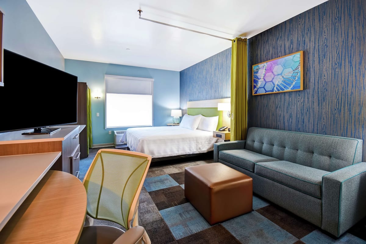 Una habitación de hotel con cama, sofá, escritorio, silla y televisión.