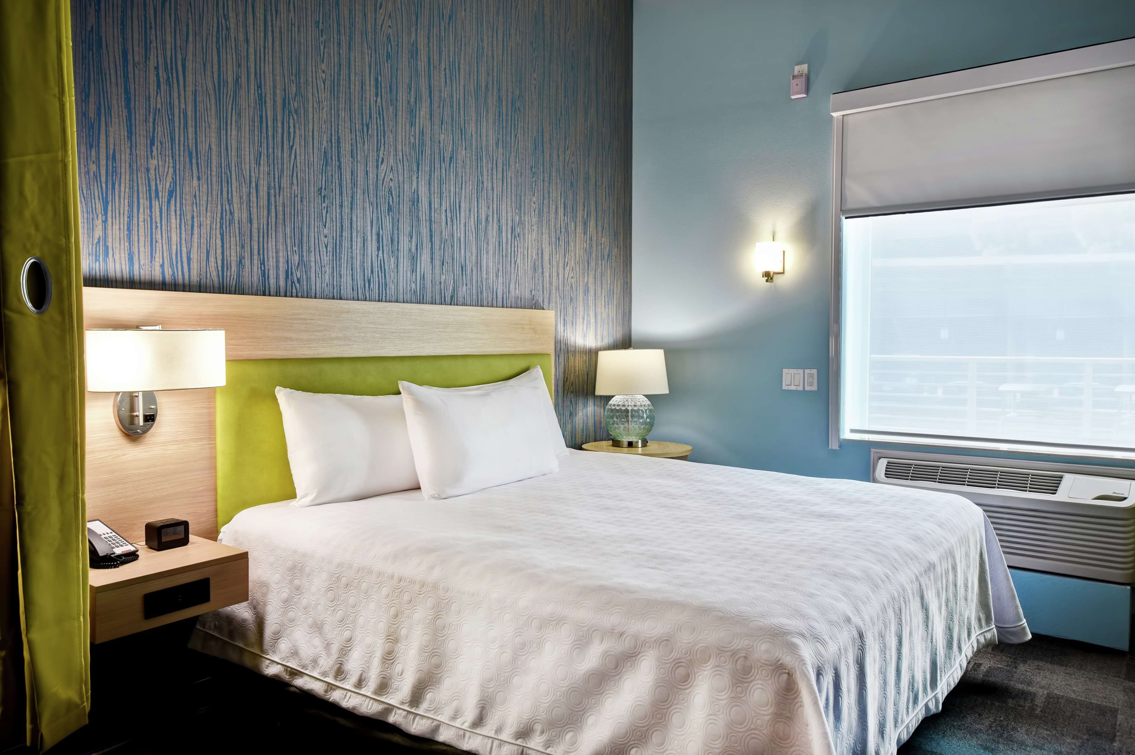 Une chambre d’hôtel avec un lit, deux lampes de chevet, un téléphone sur la table de chevet et une fenêtre donnant sur un paysage agréable.