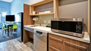Cocina compacta equipada con lavavajillas, microondas y horno integrado. Cuenta con un comedor con mesa y sillas.