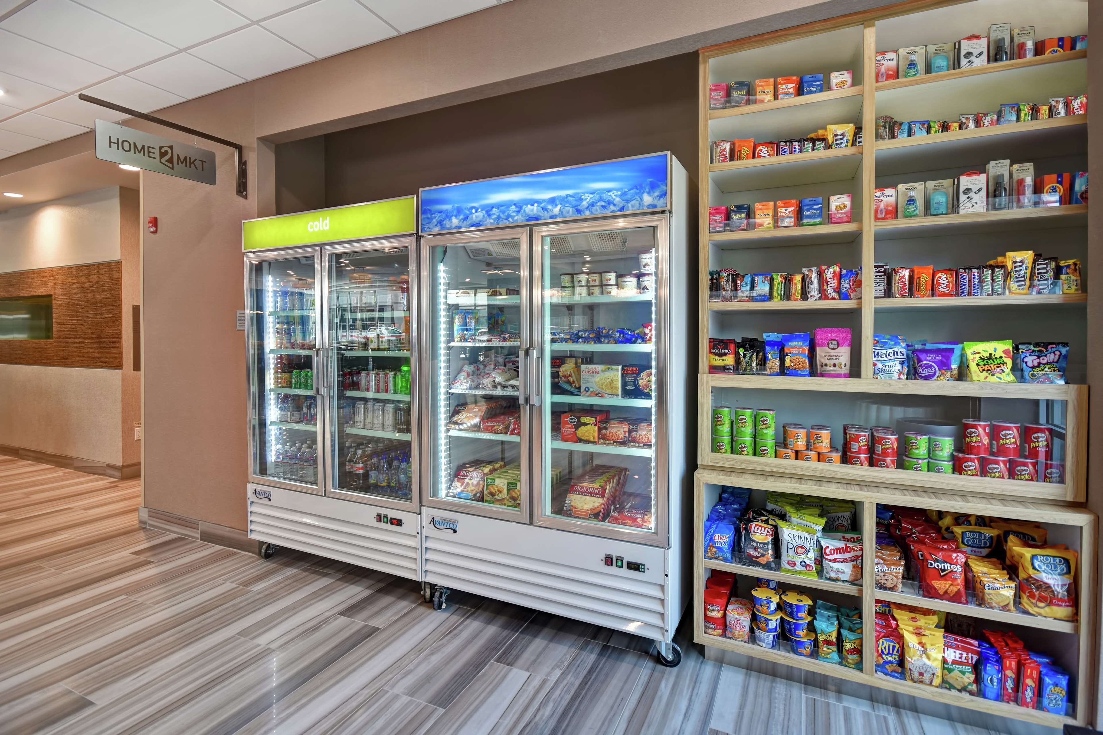 A self-service snack and beverage kiosk with refrigerated sections and shelves stocked with various snacks and drinks.