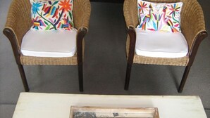 Dos sillas de mimbre con cojines estampados de flores y una mesita con estructura de estilo vintage.