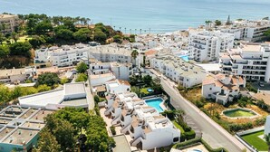A coastal residential area with white buildings, a swimming pool, and a view of the sea. - Giddah Purple Apartment, Pool, Wifi, AC (Olhos de Água)